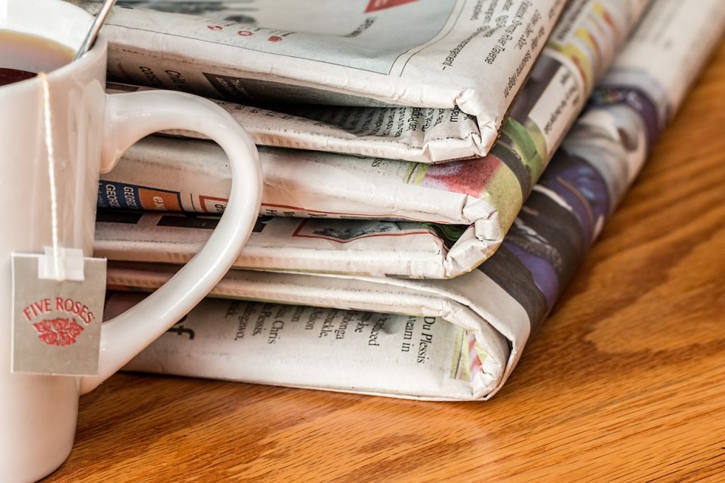 Pile of newspapers next to a mug of tea